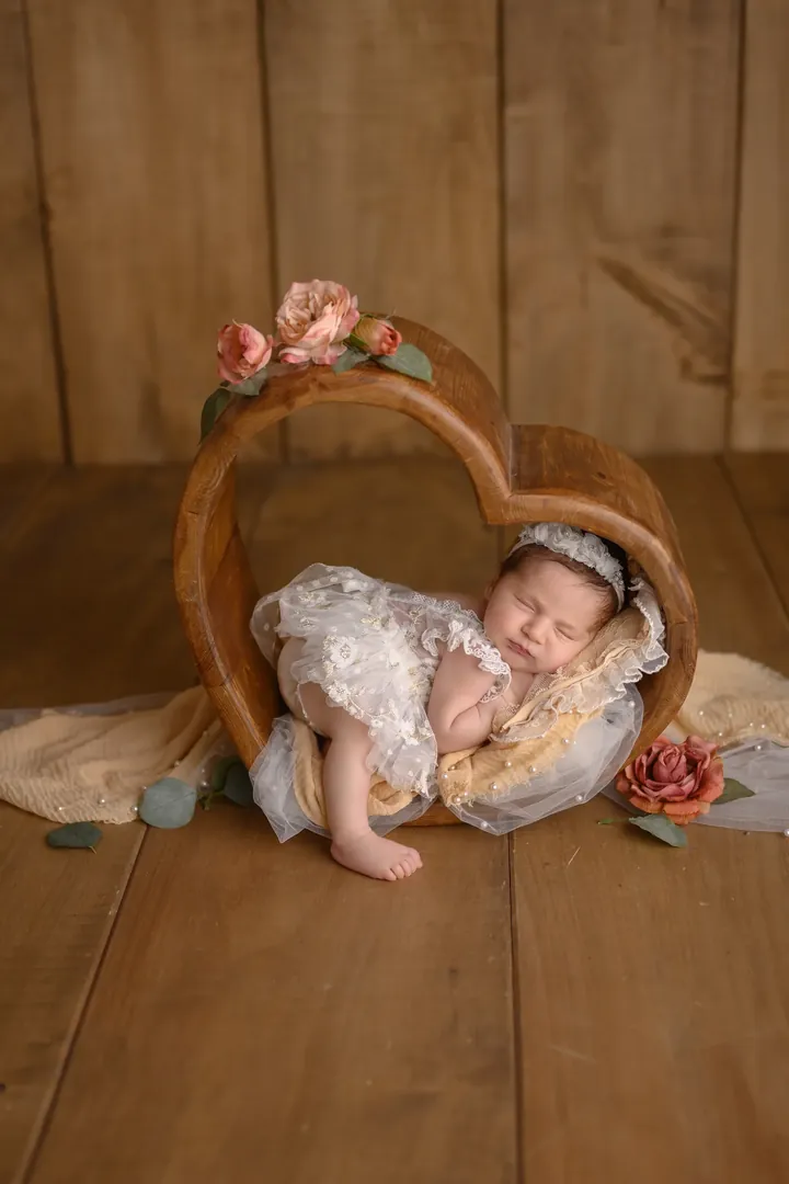 Schlafendes Neugeborenes im Holzherz mit Rosen beim Newborn-Shooting in Aarburg