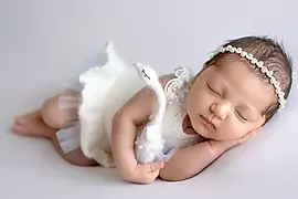 Schlafendes Neugeborenes mit Perlenhaarband beim Newborn Fotoshooting